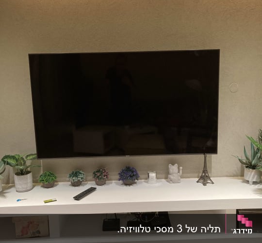 טלוויזיה תלויה על קיר עם שלט על מדף